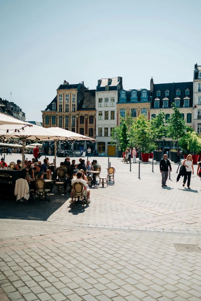 Photo d'une terrasse en ville ensoleillé avec des passants qui se promène et sont assis en terrasse