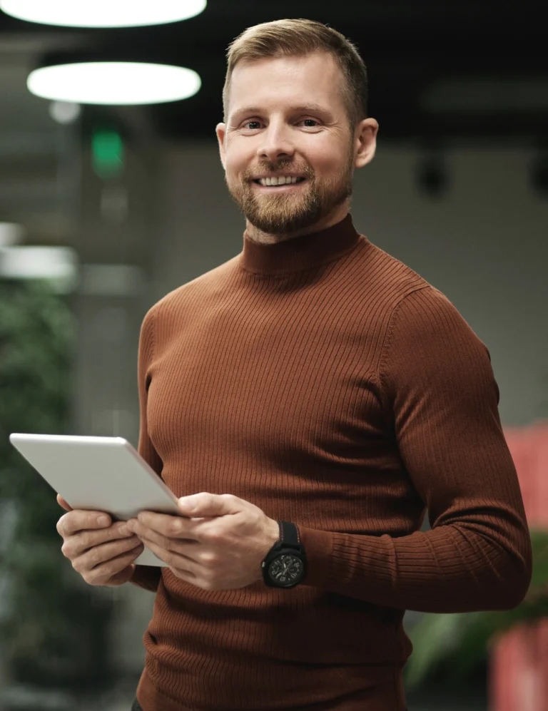 Photo d'un homme blond se tenant debout avec une tablette dans les mains, souriant